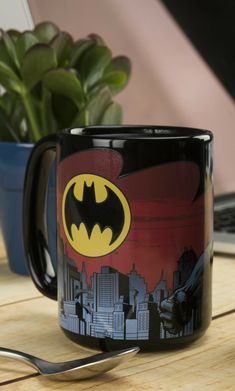 a batman mug sitting on top of a wooden table