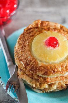 a stack of pancakes with pineapple on top and a fork next to it, sitting on a blue plate