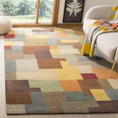 a multicolored rug in a living room next to a couch and chair with a window