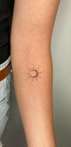 a woman's arm with a small sun tattoo on the left side of her arm