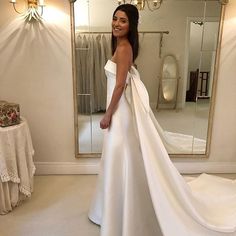 a woman standing in front of a mirror wearing a white dress