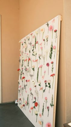 a white board with flowers on it in front of a wall and floor next to a door