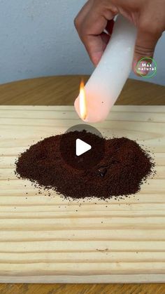 a person lighting a candle on top of a pile of coffee beans and ground cinnamons