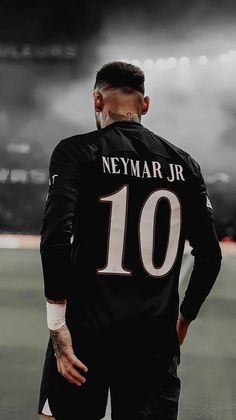 a man standing on top of a soccer field wearing a black shirt with the number ten printed on it