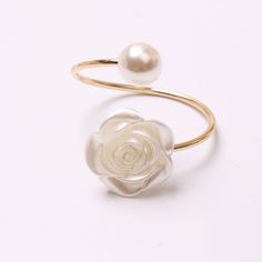 a close up of a ring with a flower and a pearl on the end of it