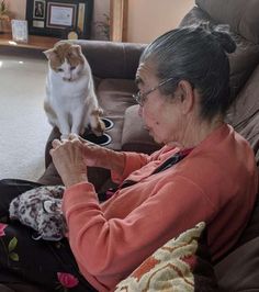 an older woman sitting on the floor next to a cat