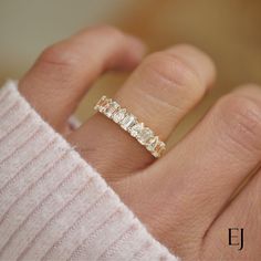 a woman's hand with a gold ring on top of her finger and a diamond band