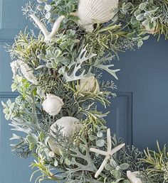 a wreath with sea shells and greenery on it