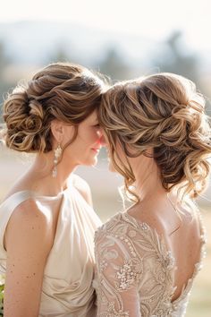 two women in wedding gowns looking at each other with their backs to the camera