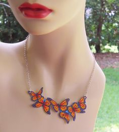 a mannequin wearing a necklace with three butterflies hanging from it's neck