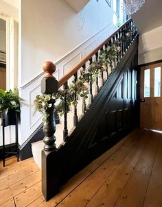 the stairs are decorated with potted plants on each baluster and chandelier