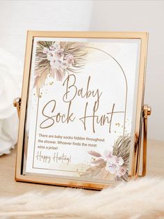 a baby book hunt sign sitting on top of a wooden table next to white flowers