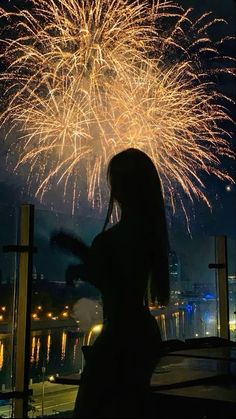 a woman standing in front of a firework display