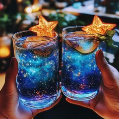 two people holding up glasses filled with liquid and stars on the top, in front of a table