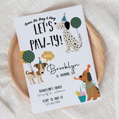 a birthday card with dogs and balloons on it sitting on top of a wooden plate