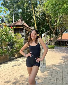 a woman standing on the sidewalk with her hands on her hips and smiling at the camera