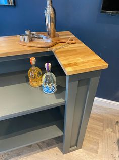 a table with two bottles on it and a cutting board next to it in front of a blue wall