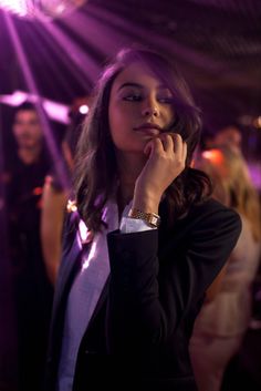 a woman in a suit is talking on her cell phone while people are standing behind her