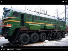 a green train is parked in the snow