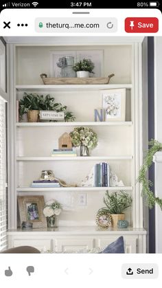 a white bookcase with plants and pictures on the top shelf, next to a window