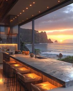 a kitchen with an ocean view and bar stools next to the counter top that is lit up at night