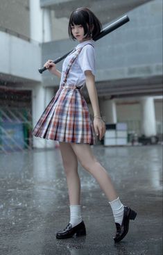 a young woman holding a baseball bat on top of a wet ground in front of a building