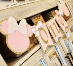 a pink and gold minnie mouse birthday banner on a mantel with wine corks in the background