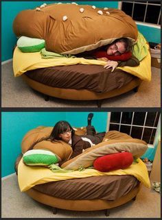 a woman laying on top of a giant hamburger bed in the middle of a room