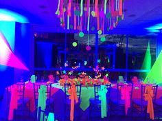 a room filled with lots of tables covered in neon colored cloths and streamers