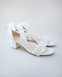 a pair of white shoes with pearls on them