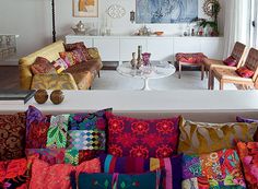 a living room filled with lots of colorful pillows and furniture on top of a white floor