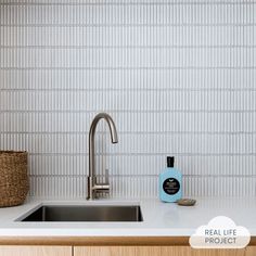 a kitchen sink sitting under a faucet next to a basket on top of a counter