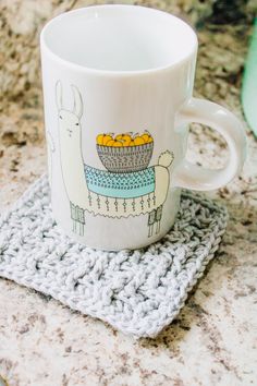 a white coffee cup sitting on top of a crocheted coaster