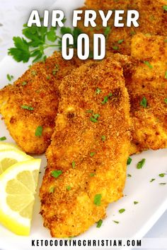 some fried food on a white plate with lemon wedges and parsley