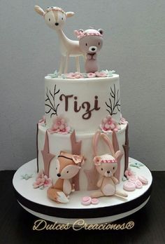 a three tiered cake decorated with pink and white frosting, animals on top