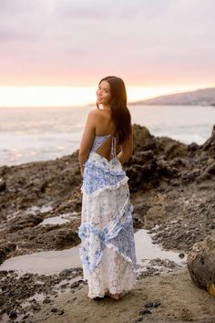 a woman in a blue and white dress standing on the beach