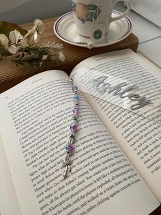 an open book sitting on top of a table next to a cup and saucer