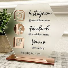 a glass plaque with the words facebook and several other social icons on it next to a potted plant