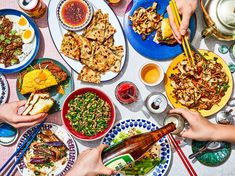 several people are eating at a table with plates and bowls full of food on it