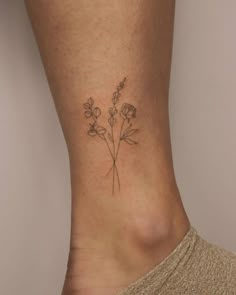 a small flower tattoo on the side of a woman's leg, with flowers growing out of it