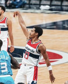 two men playing basketball in front of an audience at a sporting event, one has his hand up and the other is reaching out