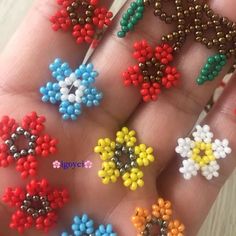 small beaded flowers are being held in someone's hand with the fingers and thumbnails