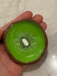 a hand holding a green bowl with a flower painted on it