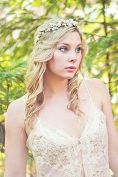 a woman with long hair wearing a white dress and flowers in her hair is looking at the camera