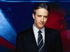 a man in a suit and tie is posing for a photo with an american flag behind him