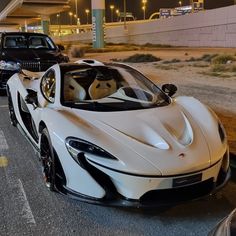 two white cars parked next to each other on the side of a road at night