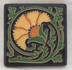 a decorative tile with an orange and yellow flower