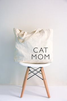 This cat mom tote bag is the perfect gift for Mother's Day for our cat lovers! An ideal tote for carrying all the things this summer! Introducing our high-quality thick canvas colored shopper tote bags, the perfect accessory for anyone looking for a durable and stylish way to carry their belongings. Made from thick and durable polyester canvas material, these bags are built to last, able to withstand daily wear and tear. The tote bag measures 15x15 with a 5 inch depth. With a spacious interior, Cotton Tote Bag With Cat Print, Everyday Cotton Bags With Cat Print, Cotton Bags With Cat Print For Everyday Use, Cotton Cat Print Bags For Everyday Use, Cotton Tote Bag With Cat Design, Everyday Canvas Bag For Mother's Day, Casual Cotton Bag With Cat Print, Cotton Canvas Bag For Mother's Day Shopping, Pet Wipes