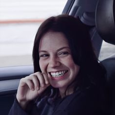 a smiling woman sitting in the back seat of a car