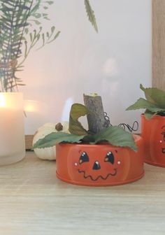 three pumpkin planters sitting on top of a wooden table next to a lit candle